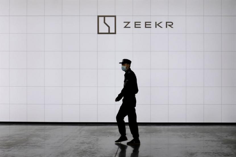Seorang petugas keamanan berjalan melewati logo kendaraan listrik (EV) premium baru Geely merek Zeekr di pabriknya di Ningbo, Provinsi Zhejiang, China.