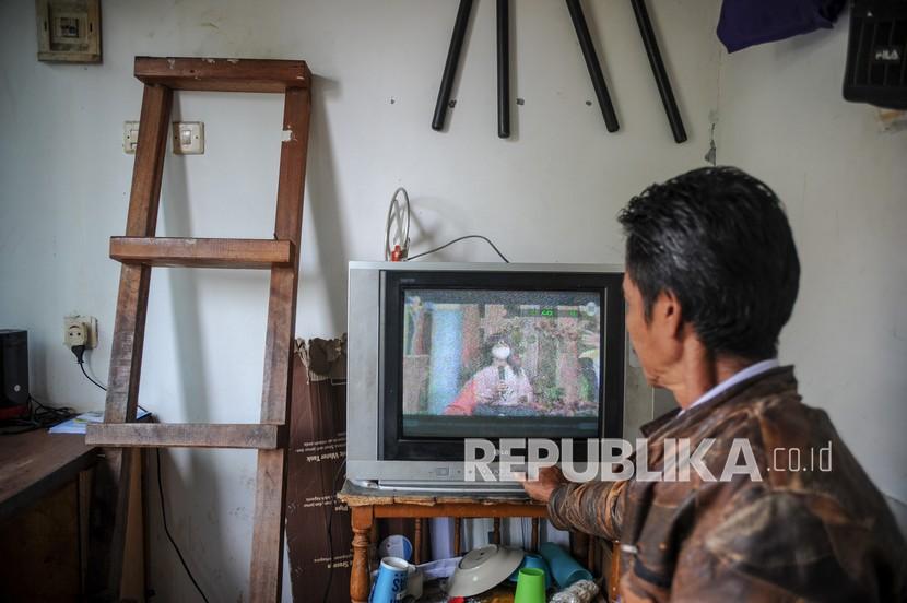Seorang petugas keamanan menonton siaran TV analog di Cinunuk, Kabupaten Bandung, Jawa Barat, Kamis (17/2/2022). Kementerian Komunikasi dan Informatika akan menghentikan siaran TV analog tahap pertama pada 30 April 2022 mendatang di 12 daerah di Jawa Barat.