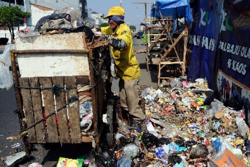 Seorang petugas kebersihan membersihkan sampah yang menumpuk di pinggir jalan (ilustrasi).