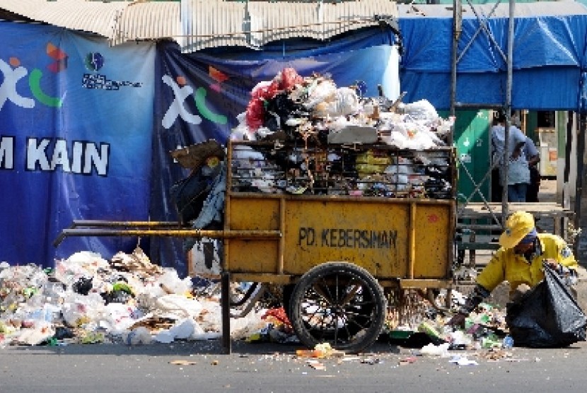 Seorang petugas kebersihan membersihkan sampah yang menumpuk di pinggir ruas Jalan Jend Ahmad Yani, Bandung, Jawa Barat.