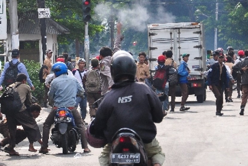 Seorang petugas kepolisian dan warga berusaha membubarkan pelajar pelaku tawuran (ilustrasi). 