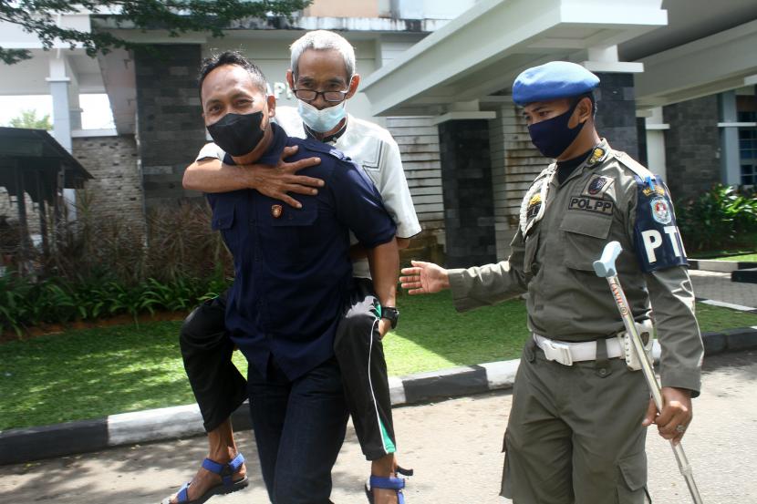 Seorang petugas kepolisian dari Polres Kubu Raya didampingi petugas Satpol PP saat menggendong warga lansia untuk diantarkan ke bus penjemput usai menjalani vaksinasi COVID-19 di Kantor Bupati Kubu Raya, Kalimantan Barat, Rabu (19/1/2022). (Ilustrasi)