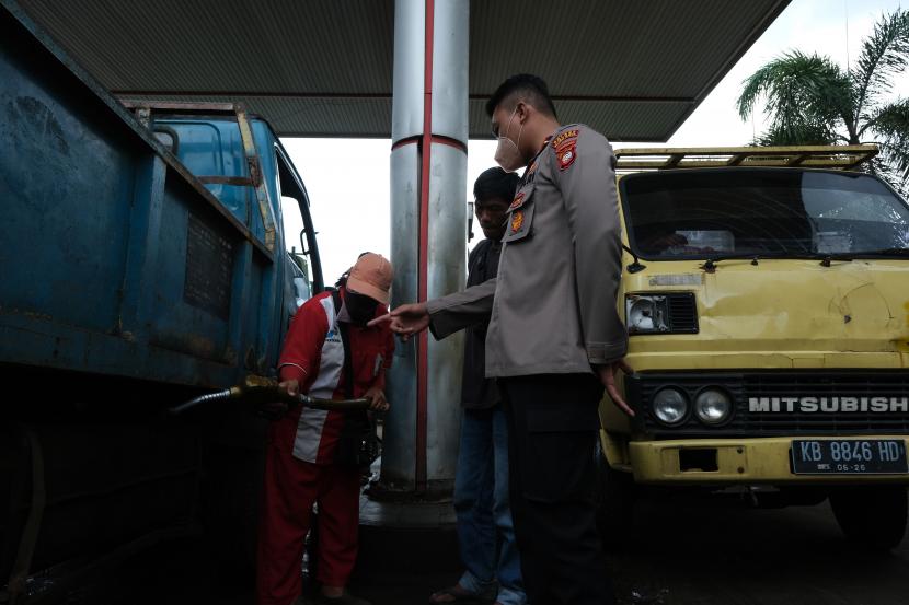 Seorang petugas kepolisian Sektor Sungai Ambawang memantau pengisian BBM jenis solar pada truk di SPBU Adau Migas Kalbar di Sungai Ambawang, Kabupaten Kubu Raya, Kalimantan Barat, Selasa (13/9/2022). 