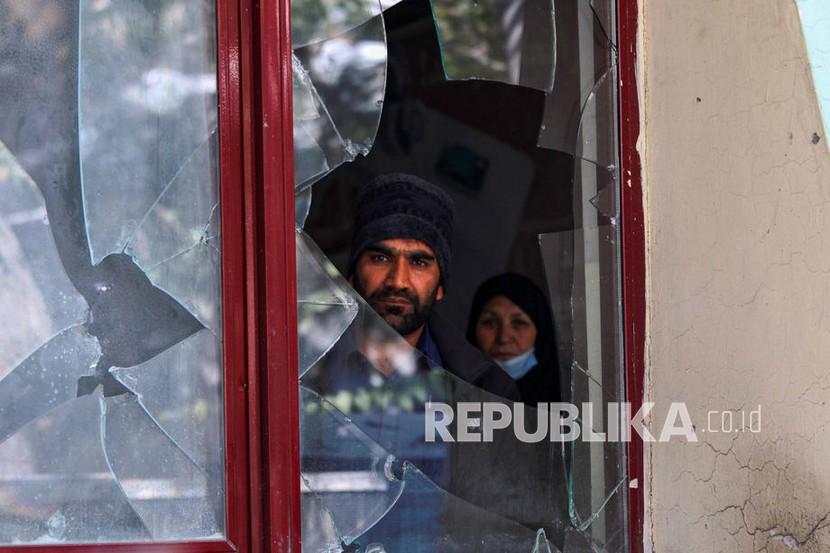 Seorang petugas kesehatan Afghanistan melihat melalui kaca jendela klinik yang hancur di depan rumah sakit militer, sehari setelah ledakan bom dan serangan oleh militan ISIS, di Kabul, Afghanistan, Rabu (3/11/2021).