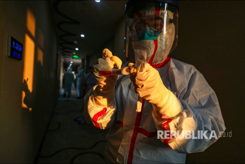 Seorang petugas kesehatan berpakaian pelindung mengumpulkan sampel dari pasien suspect terpapar virus korona di hotel yang digunakan sebagai tempat isolasi warga di Wuhan, Hubei, China, senin(3/2). 