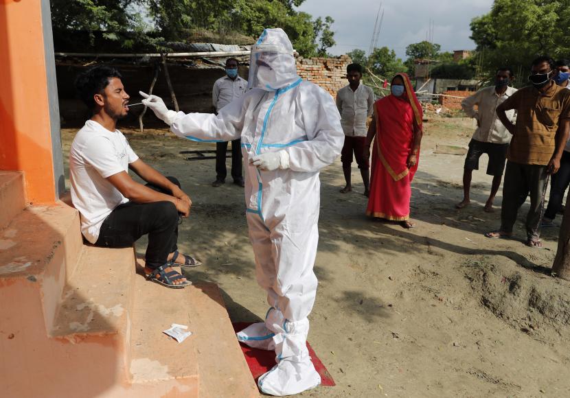 Seorang petugas kesehatan dengan pakaian pelindung mengambil sampel swab dari seorang pria untuk diuji COVID-19 sementara yang lain menunggu giliran mereka di desa Kusehta utara Prayagraj, India, Sabtu, 29 Mei 2021. 