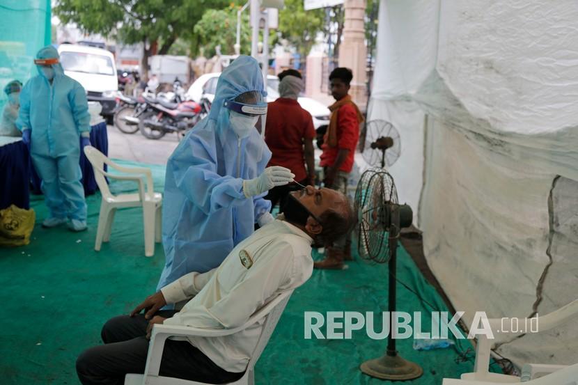  Seorang petugas kesehatan mengambil sampel usap hidung untuk tes COVID-19 di pos pemeriksaan yang didirikan untuk menyaring orang-orang yang datang dari luar kota, di Ahmedabad, India. Kasus Covid-19 global telah menembus angka 15 juta pada Kamis (23/7). Ilustrasi.