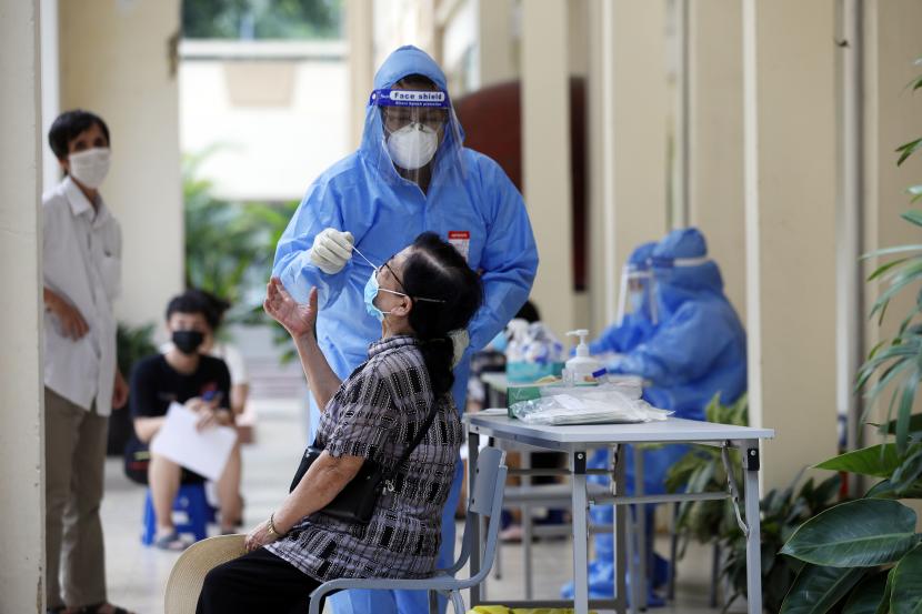 Seorang petugas kesehatan yang mengenakan alat pelindung diri (APD) mengumpulkan sampel swab dari seorang wanita untuk pengujian penyakit virus corona (COVID-19) di Hanoi, Vietnam, 13 September 2021.
