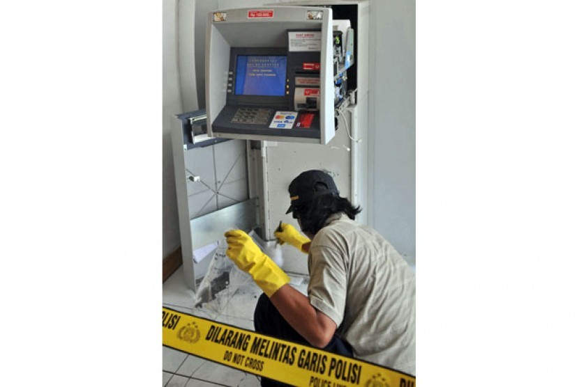 Seorang petugas melakukan identifikasi di tempat kejadian kasus percobaan pembobolan mesin anjungan tunai mandiri (ATM).