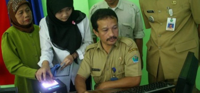 Seorang petugas melayani seorang warga saat pembuatan e-KTP.