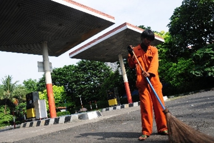 Seorang petugas menyapu lahan bekas stasiun pengisian bahan bakar umum (SPBU) di kawasan Pakubuwono, Jakarta Selatan, Ahad (1/5).
