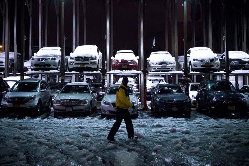 Seorang petugas parkir berjalan melewati mobil yang tertutup salju setelah diterpa badai Nor'easter di New York, Rabu (8/11). (Reuters/Andrew Burton)