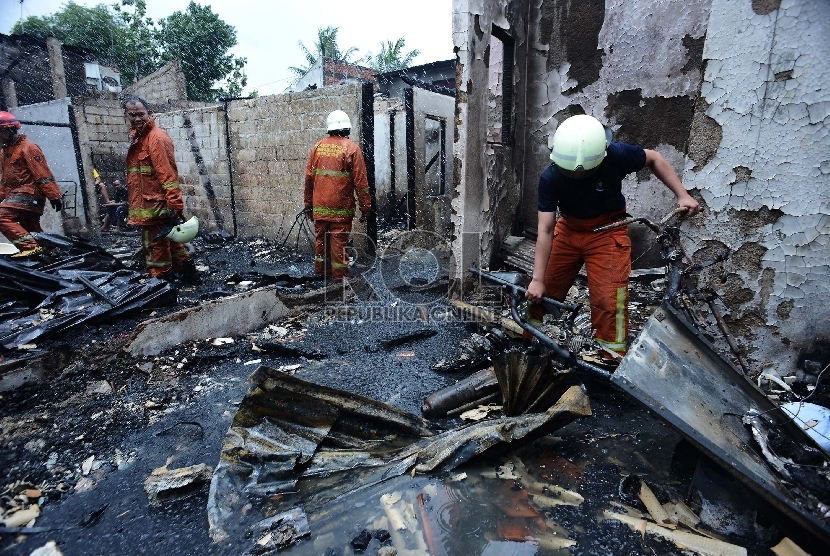 Seorang petugas pemadam kebakaran berusaha memindahkan motor yang hangus diantara puing rumah yang terbakar di Jalan Sodong Raya Timur 3, Jakarta Timur, Selasa (10/3). (Republika/Raisan Al Farisi)