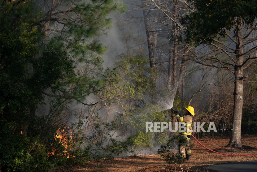 Seorang petugas pemadam kebakaran memadamkan kobaran api di area Carolina Forest di Myrtle Beach, South Carolina, Ahad (2/3/2025). 