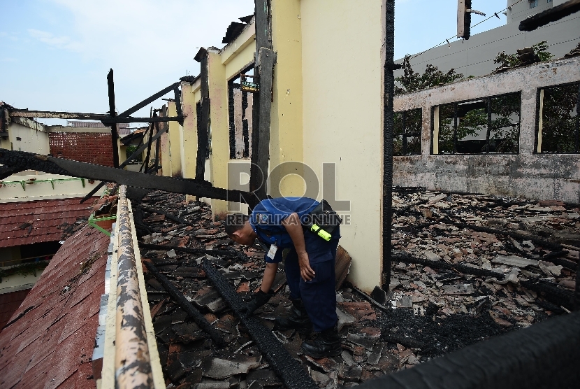 Seorang petugas pemadam kebakaran meninjau tempat kejadian perkara yang meludeskan bangunan Sekolah Menengah Pertama 65 Sunter, Jakarta Utara, Kamis (16/4). (Republika/Raisan Al Farisi).