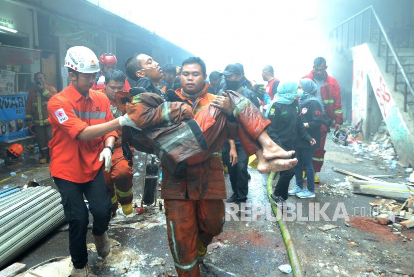 Seorang petugas pemadam kebakaran yang lemas ditolong rekannya dan petugas PMI saat peristiwa kebakaran di Pasar Kosambi, Kota Bandung, Senin (20/1).