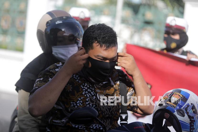 Seorang petugas polisi membagikan dan meminta pengendara untuk memakai masker pelindung saat kampanye protokol kesehatan di Banda Aceh (19/8).  