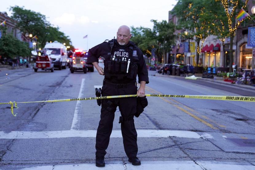 Seorang petugas polisi memegang pita polisi di lokasi penembakan massal di parade Highland Park Fourth of July di pusat kota Highland Park, pinggiran Chicago, pada Senin, 4 Juli 2022.