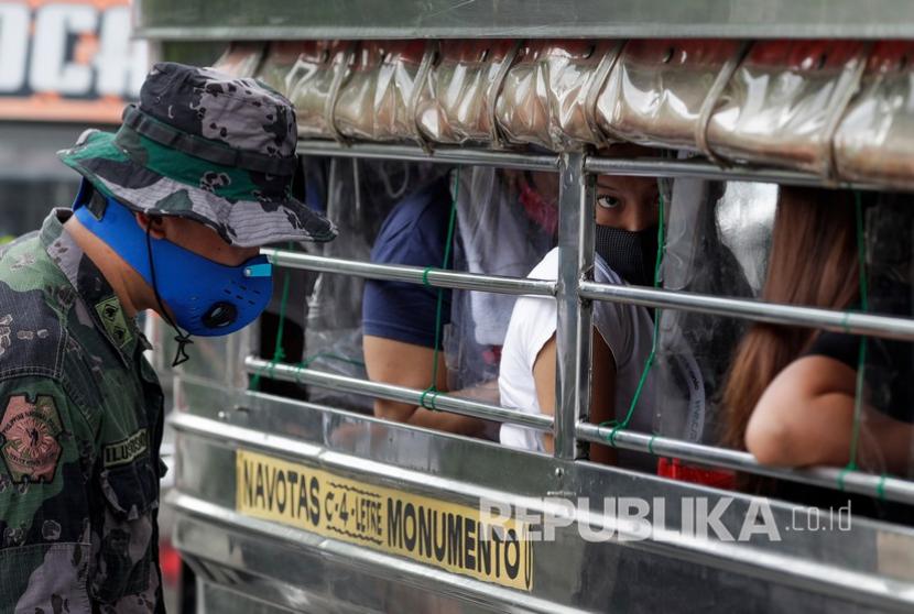  Seorang petugas polisi memeriksa penumpang  selama dimulainya lockdown karena meningkatnya kasus Covid-19 di kota Navota, Manila, Filipina, Kamis (16/7/2020). 
