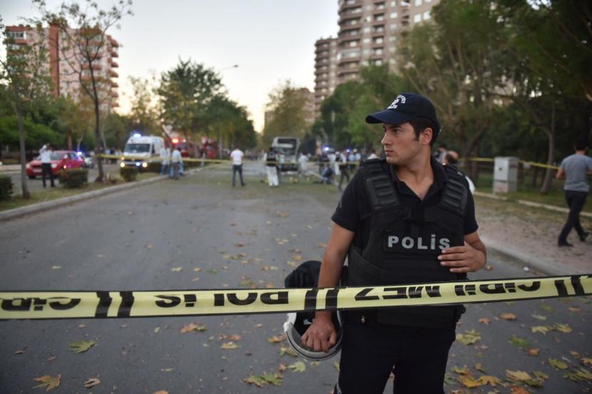 Seorang petugas polisi mengamankan sebuah area setelah ledakan di bus polisi di Mersin, Turki, 17 Oktober 2017. Sebuah bom dari sebuah kendaraan yang terparkir di jalan raya di tenggara provinsi Diyarbakir Turki meledak pada Jumat (16/12/2022).