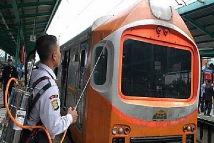  Seorang petugas PT. Kereta Api Indonesia ( PT. KAI), mengenakan alat penyemprot penumpang yang duduk di atas gerbong saat uji coba, di Stasiun Manggarai, Jakarta