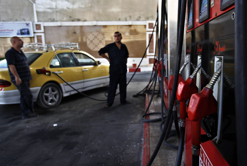  File - Seorang petugas SPBU (tengah) membantu seorang pemilik kendaraan mengisi bahan bakar di Gaza,. Setelah diblokade total selama dua pekan, Israel masih melarang pasokan bahan bakar masuk ke Gaza
