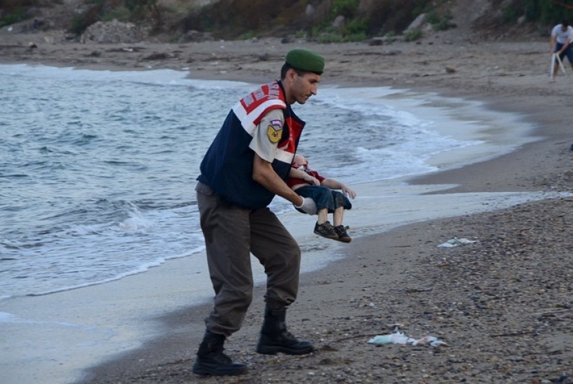 Seorang polisi membawa tubuh anak pengungsi Suriah, Alan Kurdi yang tenggelam di laut antara Turki menuju Yunani
