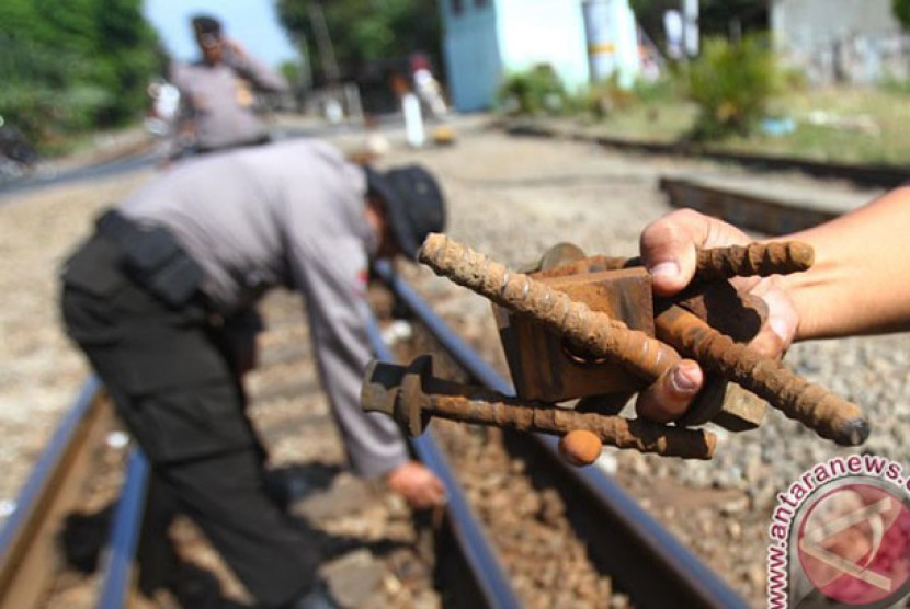 Seorang polisi memperlihatkan mur dan baut yang copot 