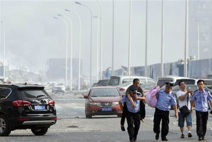 Seorang polisi menggendong warga ke tempat aman di lokasi ledakan di kota pelabuhan Tianjin, Cina, Rabu (12/8).