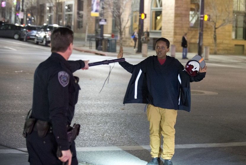 Ilustrasi - Seorang polisi menghentikan bocah laki-laki saat berjalan dari kerumunan massa, Salt Lake, Amerika.