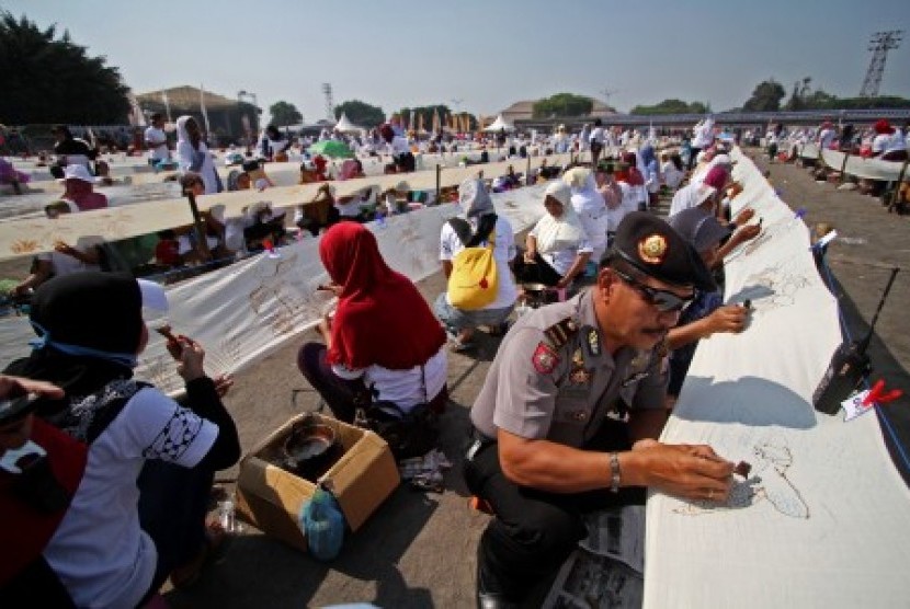 Seorang polisi tampak ikut berpartisipasi dalam kegiatan membatik kain terpanjang di dunia yang berlangsung di Yogyakarta, Kamis (2/10).