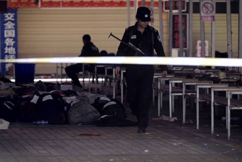 Seorang polisi terlihat berjalan di luar stasiun kereta api di barat daya Cina, Kunming. Setidaknya 29 tewas akibat serangan massal oleh sekumpulan orang tak dikenal.