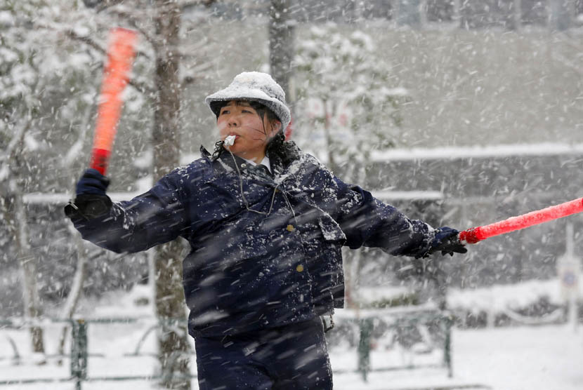   Seorang polisi wanita mengatur lalu lintas saat hujan salju di Tokyo 