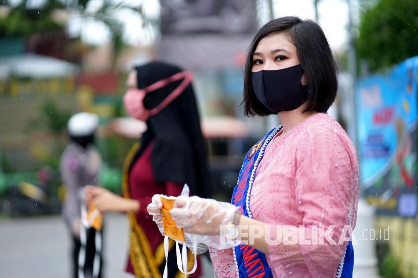Seorang polisi wanita (polwan) yang mengenakan kebaya membagikan masker kepada pengguna jalan di Kota Gorontalo. Dari total 15 pasien covid-19 di Gorontalo, baru dua orang yang dinyatakan sembuh