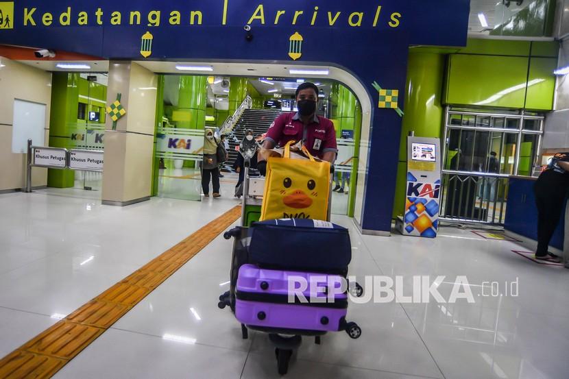 Seorang porter membawa barang milik penumpang Kereta Argo Lawu saat tiba di Stasiun Gambir, Jakarta Pusat, Senin (17/5/2021). 