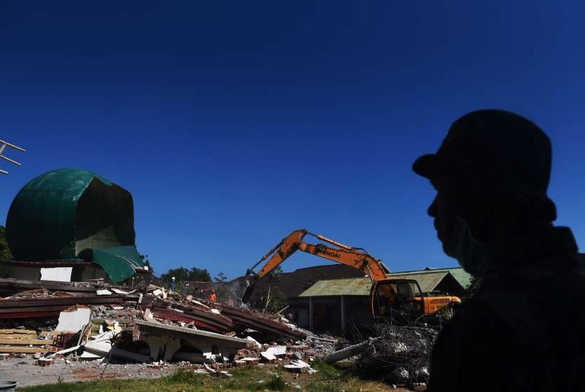 Seorang prajurit TNI AD menyaksikan anggota Basarnas berusaha mengevakuasi korban tertimbun reruntuhan Masjid Jabal Nur yang rusak akibat gempa bumi di Tanjung, Lombok Utara, NTB, Selasa (7/8). 