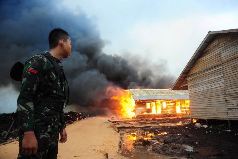 Seorang prajurit TNI menyaksikan permukiman eks-Gafatar yang dibakar massa di kawasan Monton Panjang, Dusun Pangsuma, Desa Antibar, Mempawah Timur, Kabupaten Mempawah, Kalbar, Selasa (19/1). (Antara/Jessica Helena Wuysang)