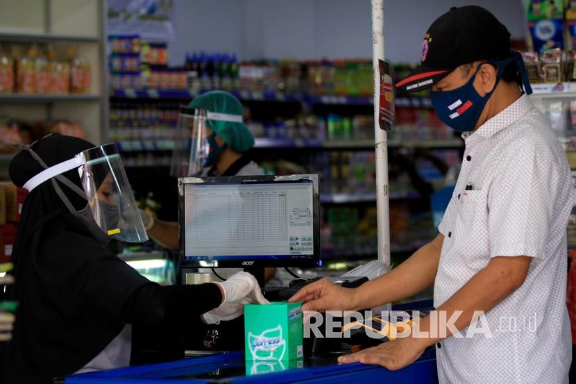 Seorang pramuniaga menggunakan pelindung wajah saat melayani pembeli di salah satu toko di Jayapura, Papua, Rabu (6/5/2020). Pemerintah Provinsi Papua memperpanjang masa tanggap darurat penanganan COVID-19 hingga 4 Juni 2020. 