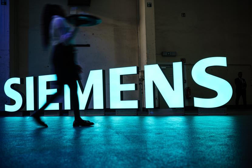 Seorang pramusaji melewati logo Siemens yang menyala saat upacara peringatan 175 tahun Siemens AG di Berlin, Jerman, 12 Oktober 2022. Siemens AG didirikan pada 01 Oktober 1847 sebagai bengkel halaman belakang di Berlin.