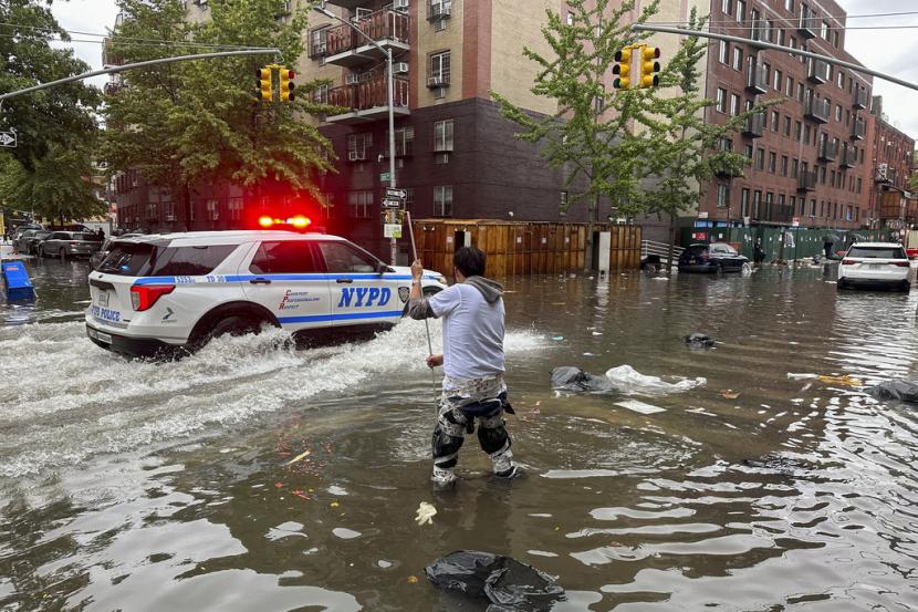 Seorang pria bekerja membersihkan saluran air akibat banjir, Jumat, 29 September 2023, di wilayah Brooklyn, New York.