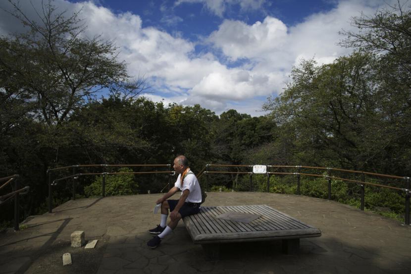 Seorang pria beristirahat di puncak gunung Hakoneyama di sebuah taman di Tokyo, Jepang, Selasa, 6 September 2022. Shoji Morimoto tampaknya memiliki pekerjaan impian semua orang: ia dibayar untuk tidak melakukan apa-apa. 