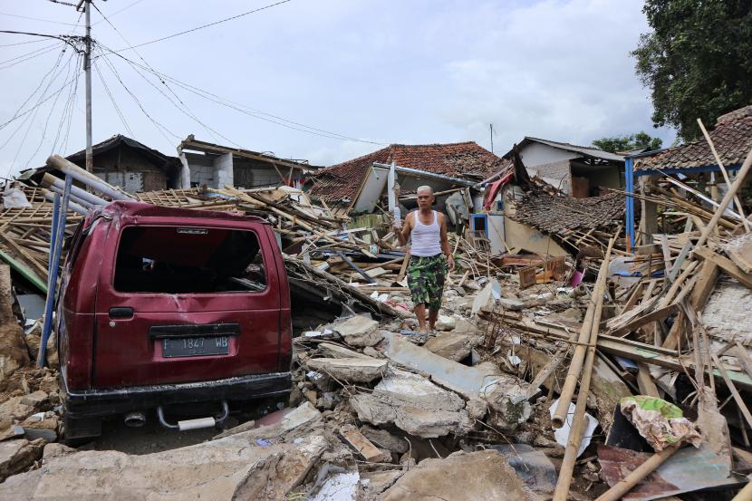 Seorang pria berjalan di atas puing-puing rumah di lingkungan yang terkena dampak gempa yang parah pada Senin, di Cianjur, Jawa Barat, Indonesia, Jumat, 25 November 2022. Gempa berkekuatan 5,6 itu menewaskan ratusan orang, banyak di antaranya anak-anak, dan melukai ribuan lainnya. 