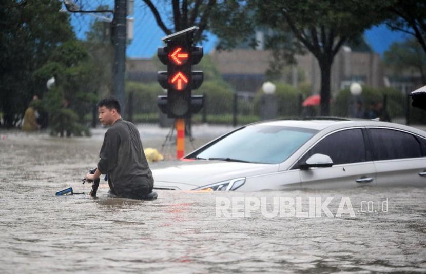  Seorang pria berjalan di jalan yang banjir setelah hujan lebat di kota Zhengzhou di provinsi Henan, China tengah, Selasa, 20 Juli 2021 (dikeluarkan 21 Juli 2021). Banjir besar di China Tengah menewaskan 12 orang di kota Zhengzhou akibat curah hujan kemarin, 20 Juli 2021.
