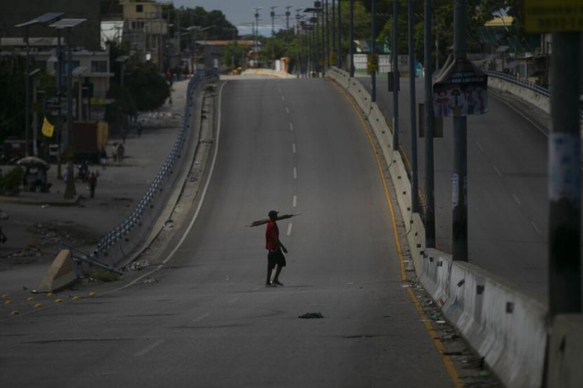 Seorang pria berjalan di sepanjang jalan utama yang dibiarkan kosong oleh pemogokan umum di Port-au-Prince, Haiti, Senin, 26 September 2022. Pemogokan itu menentang kenaikan harga bahan bakar dan menuntut agar Perdana Menteri Haiti Ariel Henry mundur.