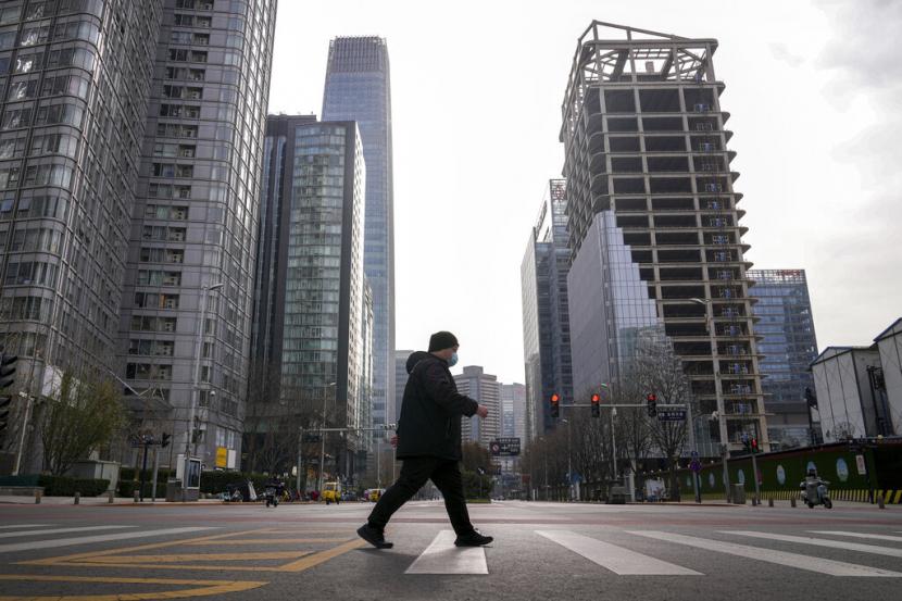 Seorang pria berjalan melalui kawasan pusat bisnis Beijing yang sepi, Senin, 28 November 2022. Pihak berwenang melonggarkan aturan anti-virus di daerah yang tersebar tetapi menegaskan strategi 