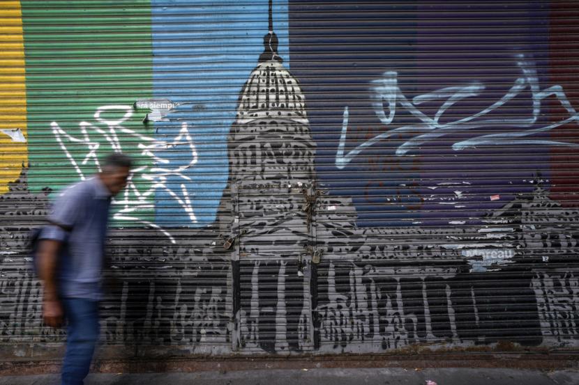 Seorang pria berjalan melewati jendela sebuah toko tertutup yang dihiasi gambar fasad Kongres, di pusat kota Buenos Aires, Argentina, Jumat, 2 Februari 2024. Inflasi Argentina pada 2023 merupakan yang tertinggi di dunia.