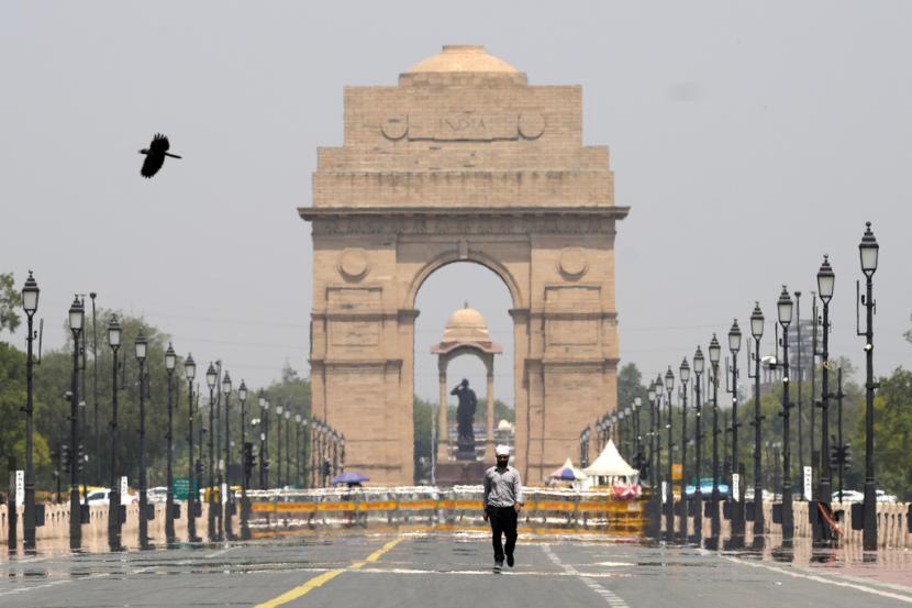 Seorang pria berjalan melewati monumen Gerbang India pada hari musim panas di New Delhi, India, Senin, 27 Mei 2024.