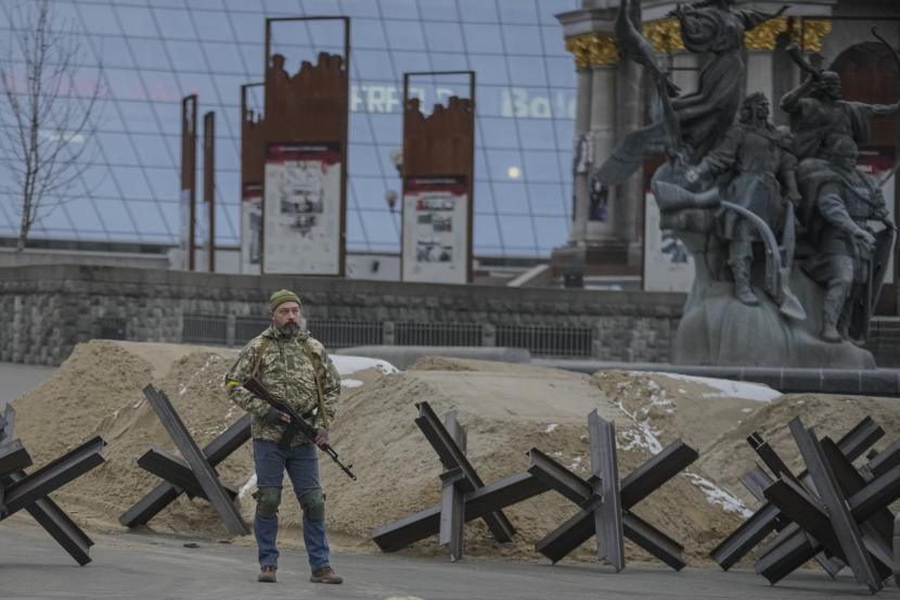 Seorang pria bersenjata berdiri di dekat barikade selama alarm serangan udara di Maidan Square, di Kyiv, Ukraina, Selasa, 1 Maret 2022.