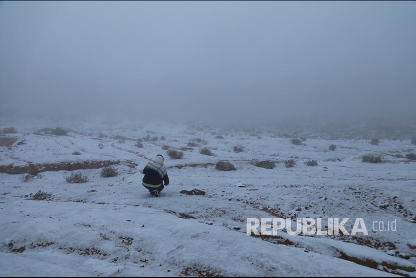 Seorang pria dengan latar  salju yang  turun di Provinsi Tabuk, Saudi Arabia, Selasa (25/2). Arab Saudi Sempat Dilanda Suhu di Bawah Nol Derajat Celsius, Kini Mulai Reda.