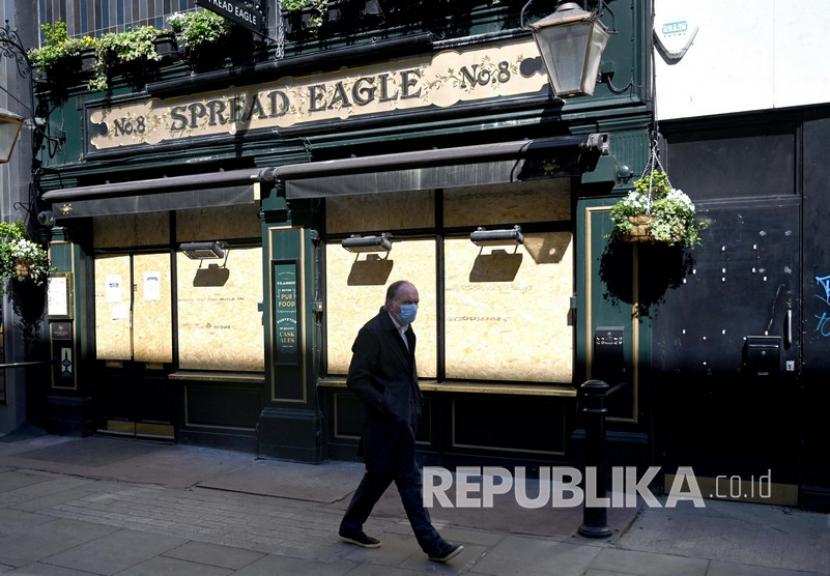 Seorang pria dengan masker melewati sebuah pub yang tutup di dekat Oxford Street di London, Inggris, Selasa (14/4). Ketua oposisi pemerintah Inggris dari Partai Buruh minta kejelasan lockdown. Ilustrasi. 